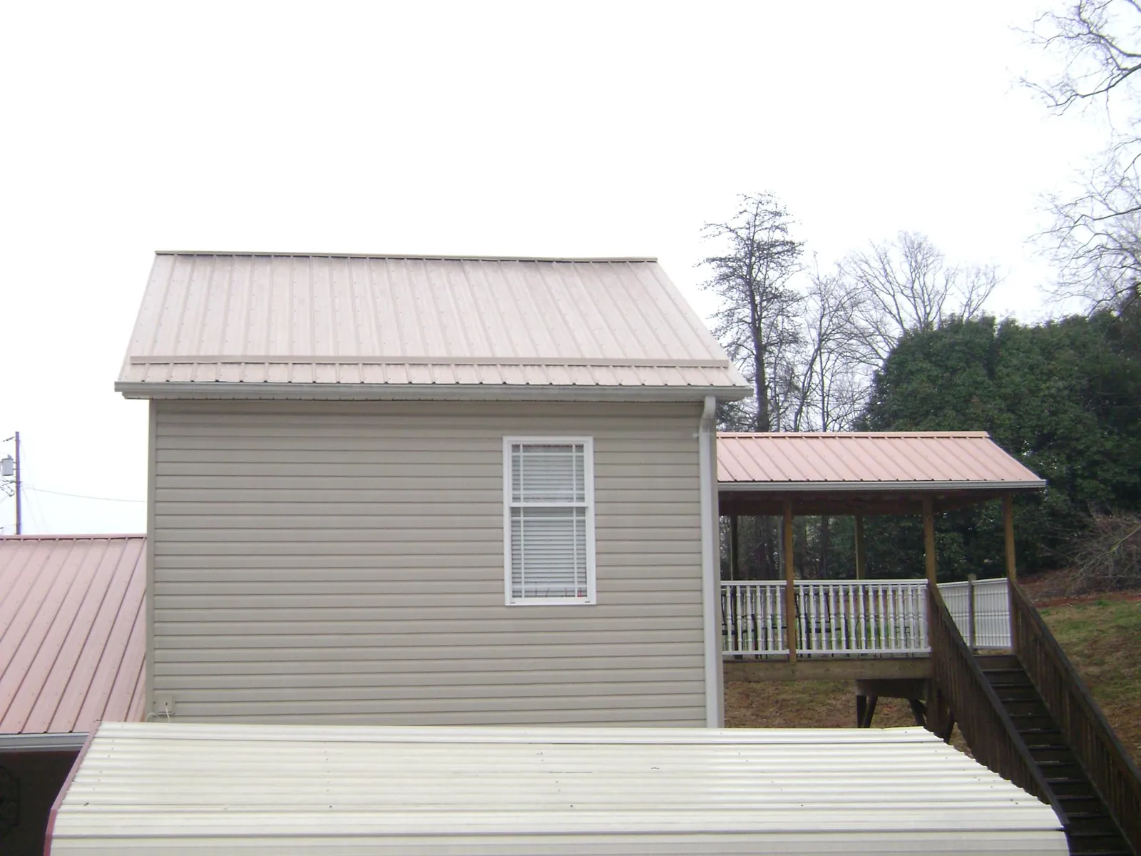 Tan metal roofs on a two story addition and attached porch, from a Roof Replacement job in Duarte