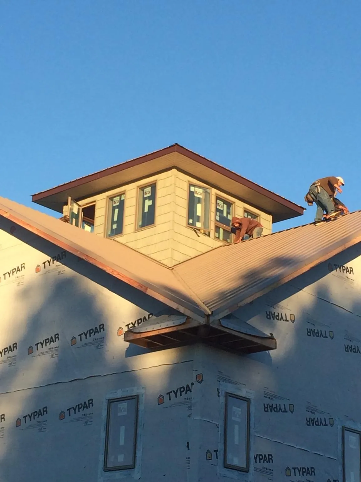 Roofers working around a rooftop cupola on a new metal roof at sunset — Roof Waterproofing in Duarte by Roofing Brothers